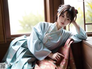 A woman in a blue kimono posing by a window.