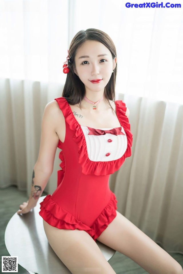 A woman in a red and white bathing suit sitting on a table.