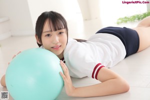 A young woman sitting on the floor with a blue ball.
