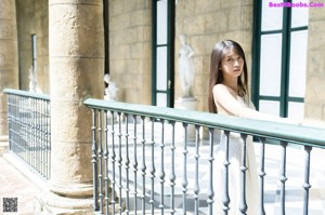 A woman in a white dress sitting on a black and white checkered floor.