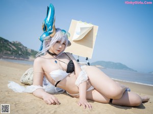 A woman in a bikini sitting on a beach.