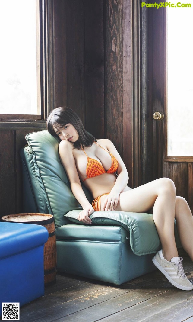A woman in a bikini sitting on a green chair.