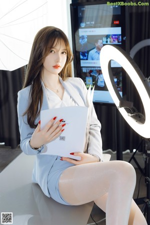 A woman sitting on top of a table next to a television.
