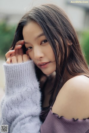 A woman sitting on a brick walkway wrapped in a blanket.