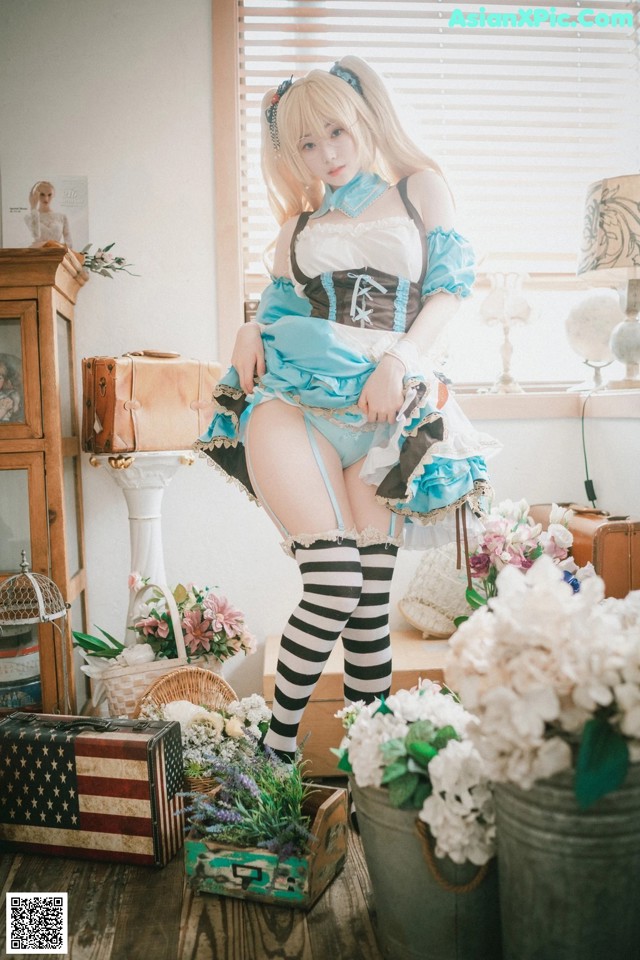 A woman in a blue and white dress sitting on a wooden floor.