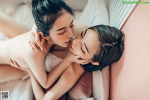 A couple of women sitting on top of a bed.
