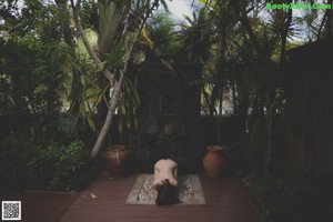 A naked woman sitting on a wooden bench.