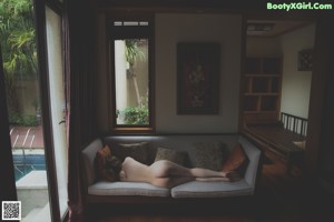 A naked woman sitting on a wooden bench.