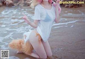 A woman in a white shirt and a cat hat on a beach.