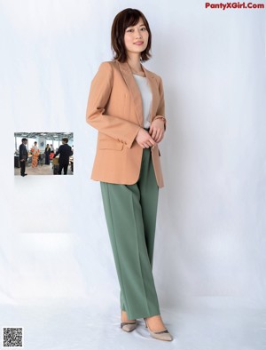 A woman leaning against a wooden wall with a smile on her face.
