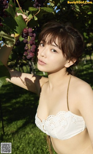 A woman laying in the grass next to a bunch of grapes.