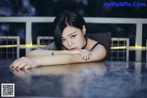 A naked woman sitting on a bed next to a lamp.