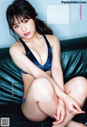 A woman with long black hair sitting on a couch.