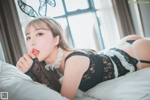 A woman in a bunny costume is posing on a bed.