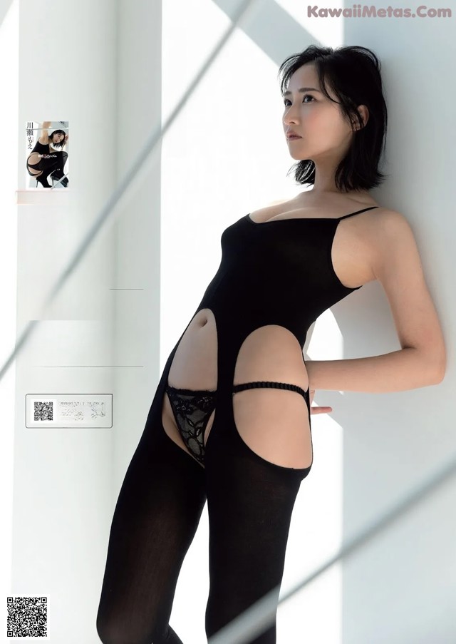 A woman in a black bodysuit leaning against a wall.