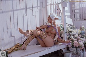 A woman in a bikini sitting on the ground next to flowers.