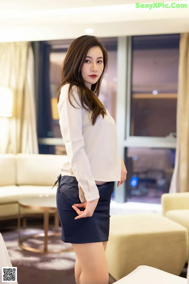 A woman in a white shirt and black skirt posing for a picture.