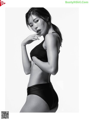 A woman in a black sports bra top and black leggings doing a yoga pose.