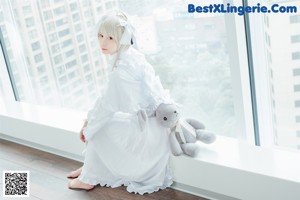 A girl in a white dress holding a stuffed animal.