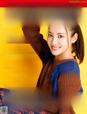 A woman in a brown sweater and blue scarf smiles at the camera.