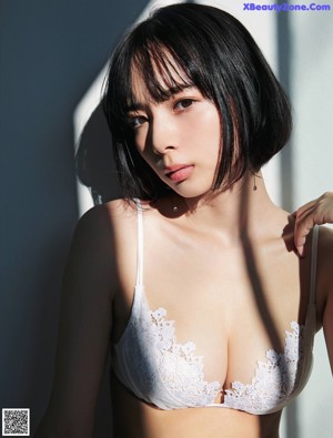 A woman sitting on a bed wearing a bra and panties.