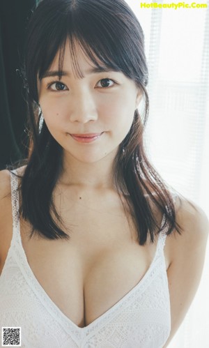 A woman in a white bodysuit leaning against a window.