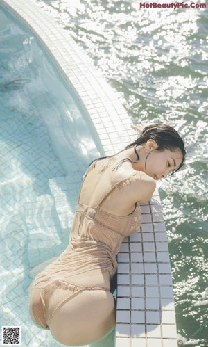 A woman floating in a swimming pool with her arms outstretched.