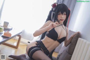 A woman in a black lingerie eating a piece of cake.