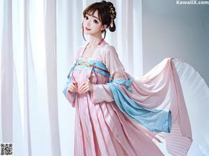 A woman in a blue and pink dress sitting on a bed.