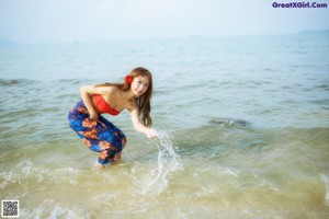A woman in a red top and blue skirt posing for a picture.