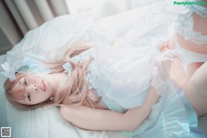 A woman in a white dress sitting on a bed.