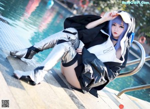 A woman with blue hair sitting on a bed.