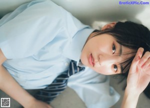 A young woman leaning against a blue wall.