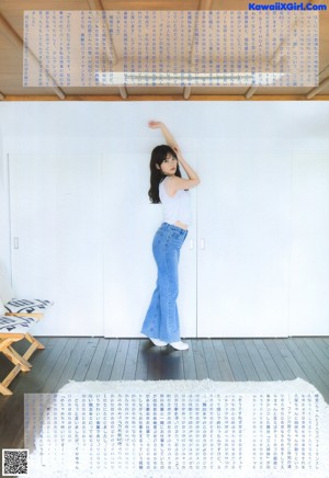 A woman in a blue dress standing in front of a window.
