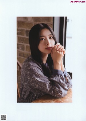 A woman standing in front of a brick wall.