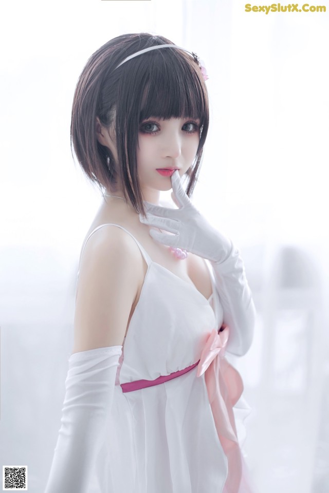 A woman in a white dress and white gloves posing for a picture.