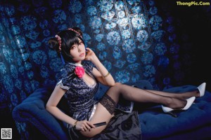 A woman in a blue dress sitting on a blue couch.
