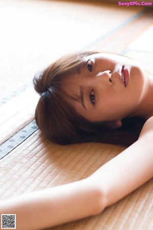 A naked woman laying on the floor in a room.